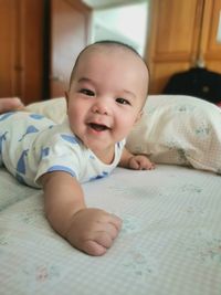 Portrait of cute baby girl lying on bed at home