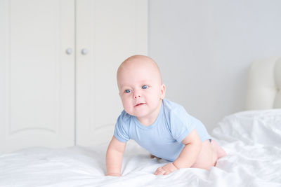 Cute baby boy lying on bed at home