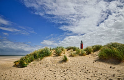 Lighthouse on beach against sky