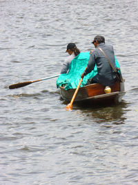 Rear view of men sitting on boat in sea