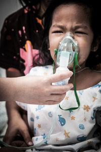 Cropped image of doctor putting mask on crying girl