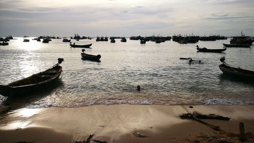 Boats moored on sea against sky during sunset