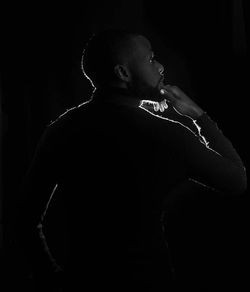 Midsection of man playing guitar against black background