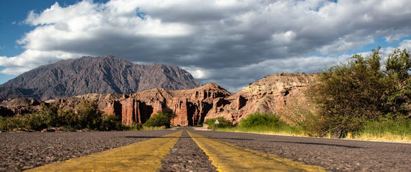 Road by mountains against sky