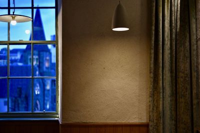 Illuminated lamp on wall by window