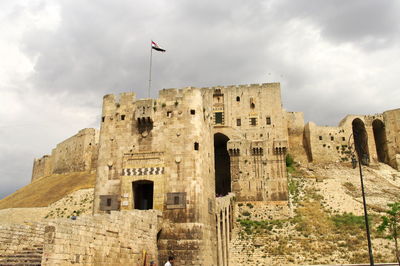 Aleppo castle, low angle view of old building against cloudy sky