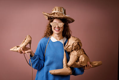 Portrait of woman wearing hat standing against yellow background