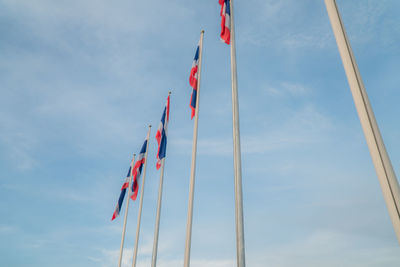 Low angle view of thai flags in row against sky