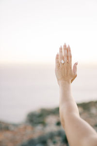 Cropped image of hand against sea