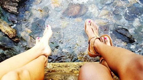 Low section of women relaxing on rock at lakeshore