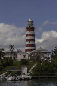 Lighthouse by building against sky