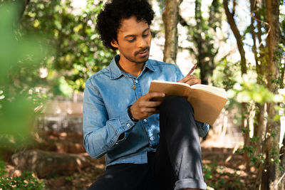 Man writing in book at park