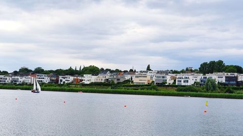 Buildings by river against sky in city