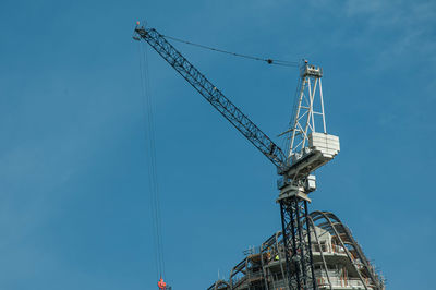 Low angle view of crane against blue sky