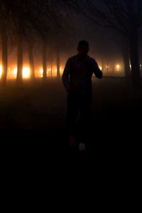 Silhouette man standing on illuminated field at night