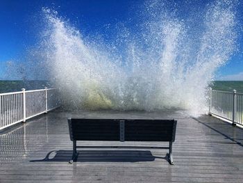 Empty bench on sea against sky