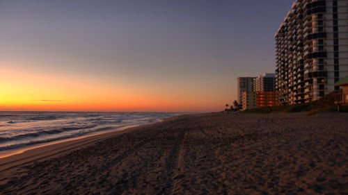 Scenic view of beach against clear sky during sunset