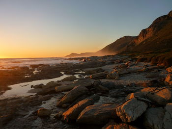 Scenic view of rocks against clear sky during sunset