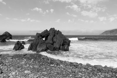 Rock formation on beach against sky