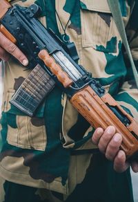 Midsection of army soldier with gun standing at outdoors