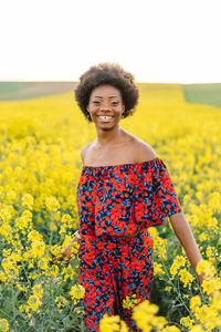 Portrait of a smiling young woman standing on field