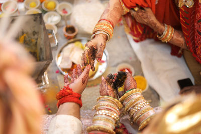 Mother putting turmeric on the hands of bride and groom for good luck during wedding