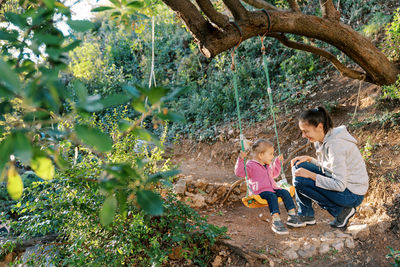 Low angle view of boy sitting on tree