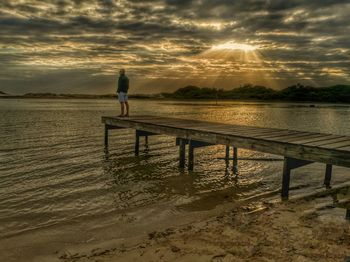 Man standing on beach against sky during sunset