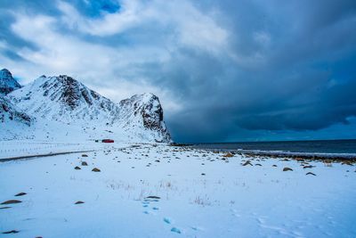 Scenic view of snowcapped mountains by sea against sky