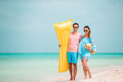 Portrait of couple standing on beach against sky