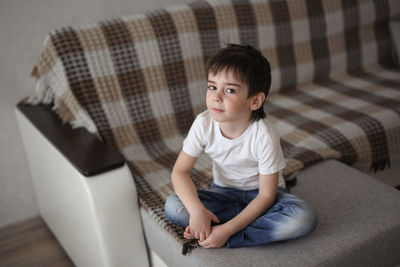 Portrait of a brunette child boy with gray eyes, in a real home interior