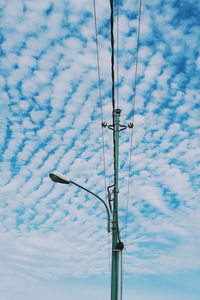 Low angle view of power lines against cloudy sky