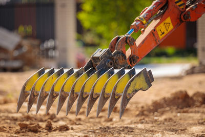 A mini excavator with a rake loosens the ground. landscape preparation