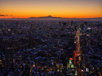 Illuminated cityscape against sky at sunset