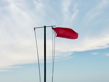 Low angle view of red flag against sky