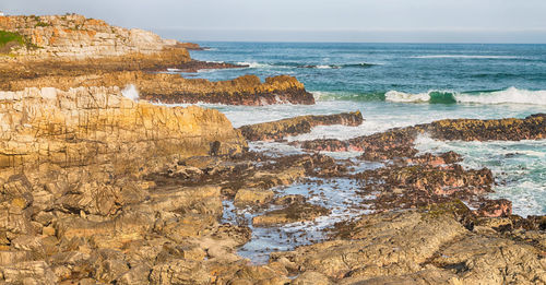 Rock formation on beach against sky