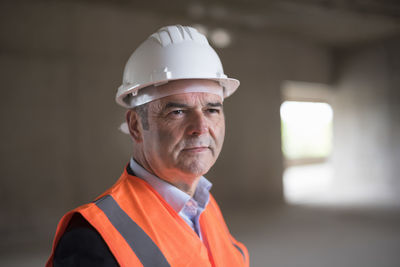 Portrait of man wearing safety vest in building under construction
