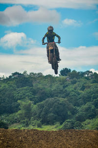 Man climbing on land against sky