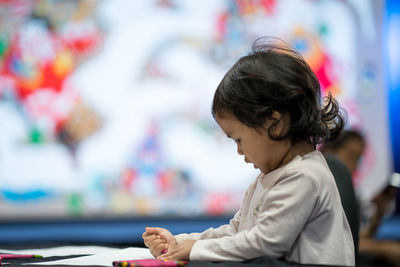 Side view of girl drawing on paper