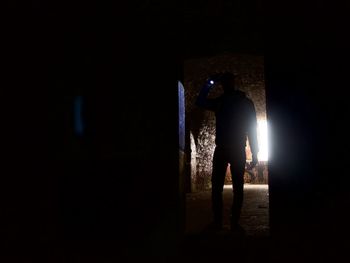 Silhouette man standing in illuminated room