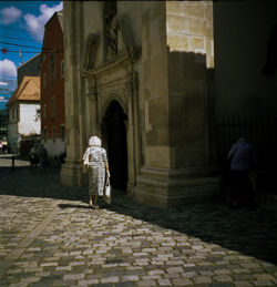 Rear view of people walking on street amidst buildings