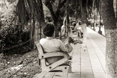 Rear view of man sitting on tree trunk