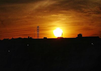 Silhouette electricity pylon against sky during sunset