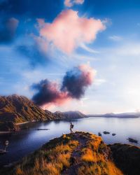 Person standing on land against sky during sunset