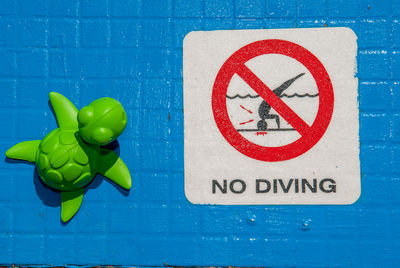 Close-up of warning sign on blue wall