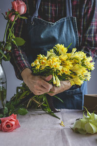 Unrecognizable female professional florist making bouquets of various types. roses. yellow flowers. coves