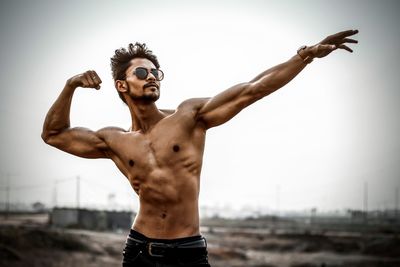 Shirtless man standing against sky