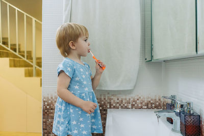 Little toddler girl brushes her teeth in the bathroom.