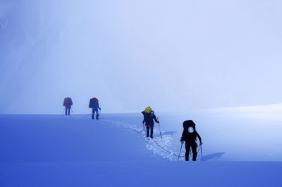 People hiking on snowcapped mountain against sky
