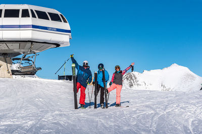 People on snow covered mountain against blue sky